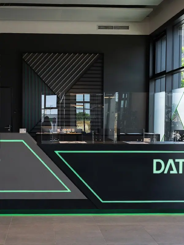 Dunkle Empfangstheke mit grün leuchtenden Kanten in einem Foyer mit Glasfront